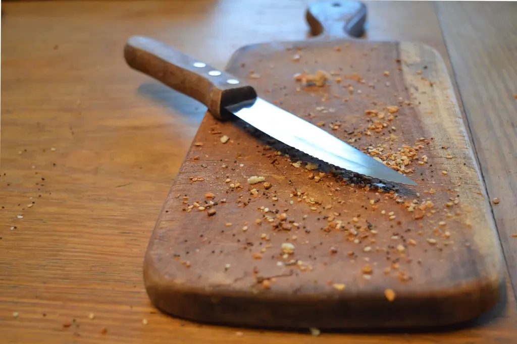 Well-worn wooden cutting board with a kitchen knife