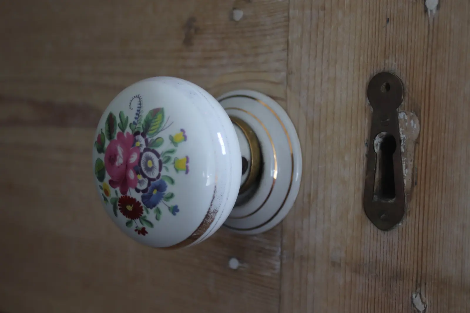 Antique painted porcelain doorknob and keyhole on an old wooden door