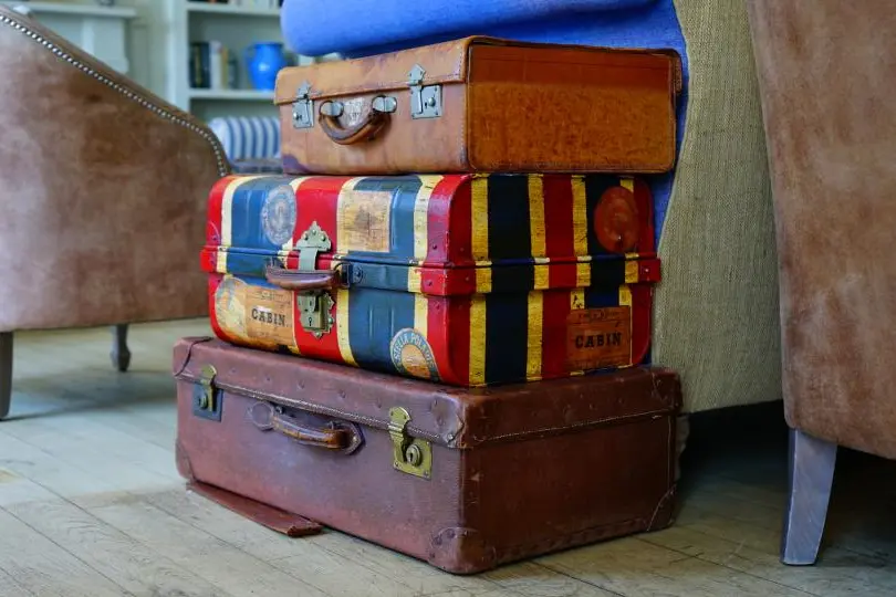 Stack of vintage suitcases beside old furniture at an estate sale