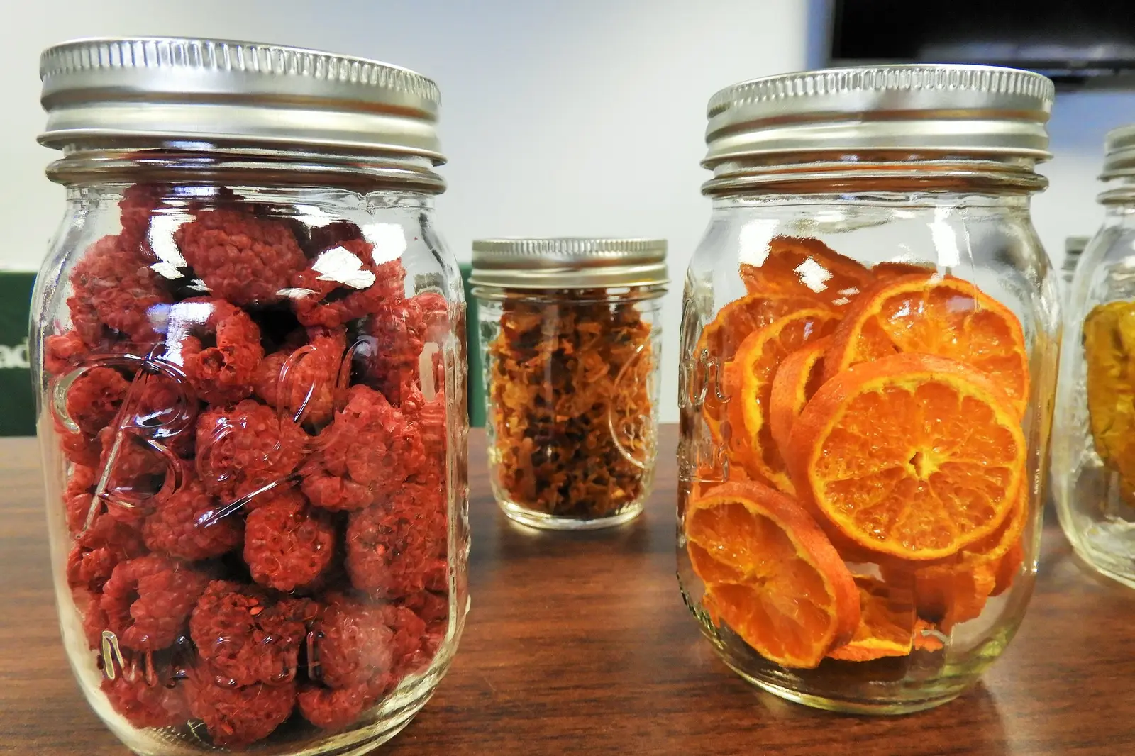 Mason jars filled with dried raspberries and dried orange slices