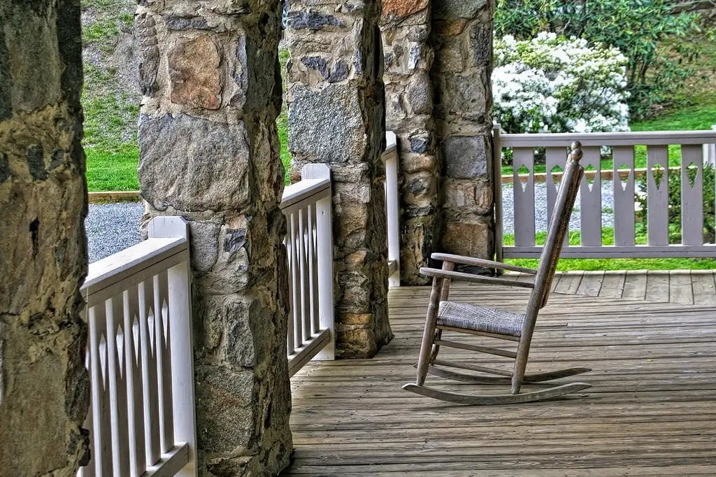 Wooden front porch with a rocking chair and stone pillars