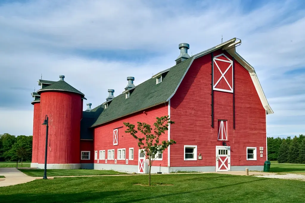 Classic red barn with white trim and a silo under a blue sky
