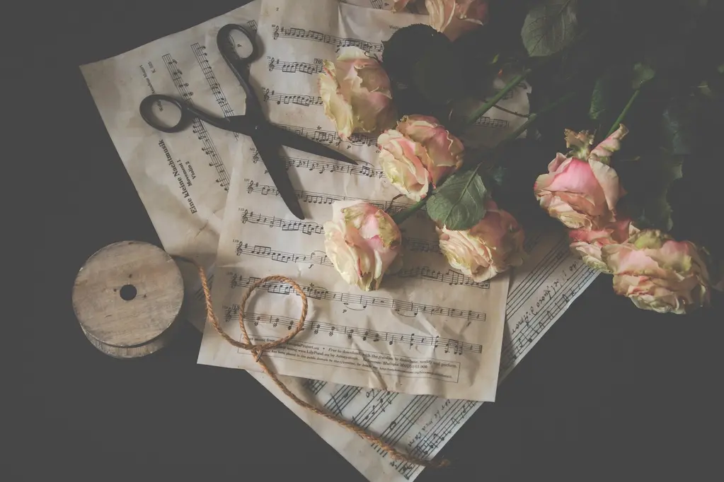 Old sheet music with dried roses, scissors and twine