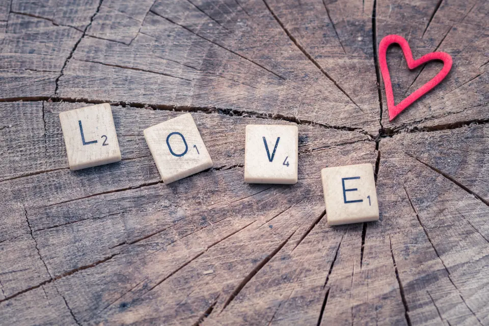 Wooden letter tiles spelling LOVE with a red heart on a wood slice